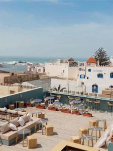 uma vista para um pátio com cadeiras e mesas e para o oceano em Le Palazzo em Essaouira