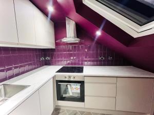 Fioletowa kuchnia z białymi szafkami i kuchenką w obiekcie High Standard Room, Super Location w Londynie