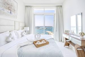 a white bedroom with a large bed with a desk and windows at Elegant 1BR Apartment with Sea View and Free Beach Access in Dubai +37 photos