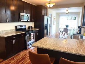 a kitchen with brown cabinets and a counter top at The House Hotels - W20TH - Three Bedroom, Near West Side Market and Downtown Cle in Cleveland