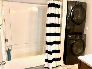 a shower curtain in a bathroom next to a washing machine at The House Hotels - W20TH - Three Bedroom, Near West Side Market and Downtown Cle in Cleveland +39 photos