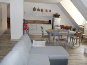 a living room with a couch and a table and a kitchen at CHARMANT APPARTEMENT DANS MAISON DE CARACTERE in Saint-Brice-sur-Vienne