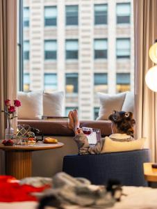 une femme assise sur une chaise devant une fenêtre dans l'établissement L7 Chicago by LOTTE, à Chicago