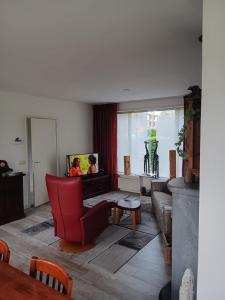 uma sala de estar com uma cadeira vermelha e um sofá em Hoekhuis met tuin op het zuiden. em Gouda
