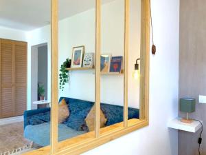 a mirror in a living room with a blue couch at Cosy 2 pièces au coeur de la ville à 10 min du centre de Paris in Maisons-Alfort