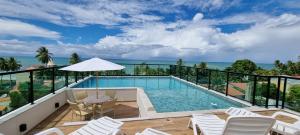 a swimming pool with chairs and a view of the ocean at Rooftop103-Tamandaré in Tamandaré