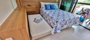 a small bedroom with a bed with blue pillows at Rooftop103-Tamandaré in Tamandaré +37 photos