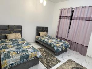 2 Betten in einem Zimmer mit Vorhängen in der Unterkunft 2bhk oasis tower in Ajman 