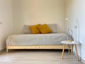 a bed with yellow pillows and a table in a room at Dimora La Coccinella - Accommodation in Muravera +3 photos