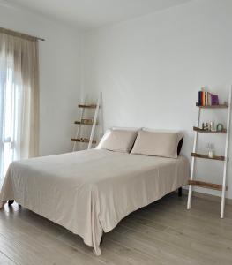 a white bed in a room with a white wall at Dimora La Coccinella - Accommodation in Muravera