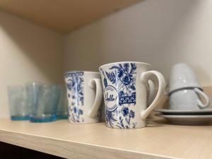 three blue and white cups sitting on a shelf at ApartVilla Trieste in Trieste