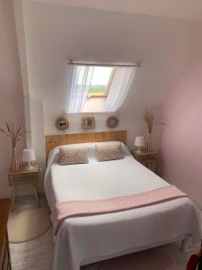 um quarto com uma grande cama branca e uma janela em Les Grillettes em Ploërmel