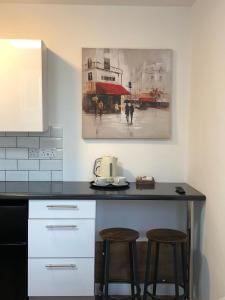 eine Küchentheke mit zwei Hockern und einem Gemälde an der Wand in der Unterkunft Studio in Bolton town, Short stay studio 5, in Bolton