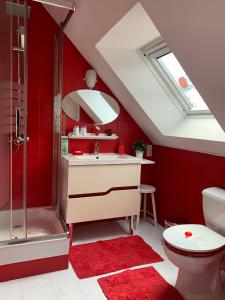 a bathroom with red walls and a sink and a shower at Les Grillettes in Ploërmel