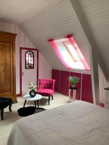 a bedroom with a bed and a pink chair at Les Grillettes in Ploërmel