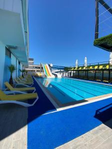 - une piscine avec des chaises longues jaunes à côté d'un bâtiment dans l'établissement ATAŞ AQUA OTEL AVŞA, à Samanlı