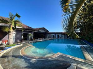 a swimming pool in front of a house with a palm tree at Ice Bear Bar & Tourist Inn in Dauis