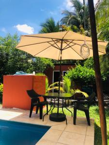 a table with an umbrella next to a pool at Casa Familiar Birds, Puerto San Jose in La Barrita