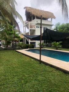 a house with a pool and a hammock in front of it at Casa Familiar Birds, Puerto San Jose in La Barrita