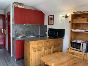 a kitchen with red cabinets and a microwave at Studio Les Menuires, 1 pièce, 4 personnes - FR-1-452-138 in Les Menuires