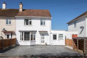 a white house with a driveway in front of it at Modern Three Bedroom Gloucester Home in Gloucester