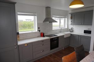 a kitchen with white cabinets and a sink and windows at 18 Ballybunion Holiday Cottages in Ballybunion