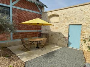 a table with an umbrella next to a brick building at Clos Margot in Le Mans