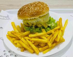 un plato blanco con una hamburguesa y papas fritas en Karinho Hotel, en Santo André