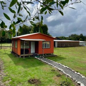 a small red house in a grass field at Cabaña Curacautín, IX Región in Curacautín