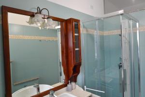 ein Bad mit einer Dusche, einem Waschbecken und einem Spiegel in der Unterkunft Appartamento Anto vicino al lago ai servizi al centro in Levico Terme