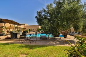 un patio con sillas, una mesa y una piscina en Essaouira Lodge en Esauira