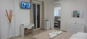 Camera bianca con letto, scrivania e TV. di AMARE Bed & Breakfast a Rodi Garganico