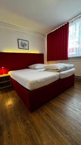 a large bed in a room with red curtains at Hotel Gifhorn INN in Gifhorn