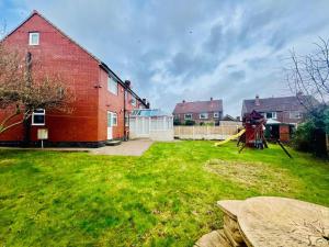 a yard with a red brick house and a playground at Sweet Home in Manchester