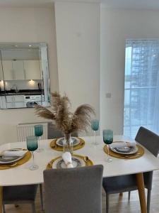 a dining room table with plates and wine glasses at Contemporary Urban Retreat, 2-Bedroom Haven by London City Airport in London