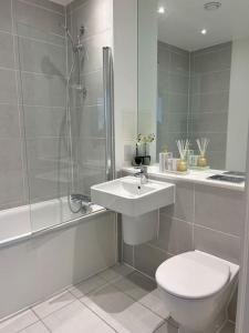 a bathroom with a toilet and a sink and a shower at Contemporary Urban Retreat, 2-Bedroom Haven by London City Airport in London