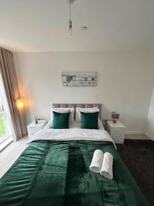 a bedroom with a large green bed with two green pillows at Contemporary Urban Retreat, 2-Bedroom Haven by London City Airport in London