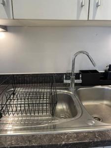 a kitchen sink with a dish drying rack on it at Contemporary Urban Retreat, 2-Bedroom Haven by London City Airport in London