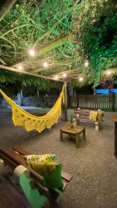 a patio with a hammock and benches and lights at Pousada Chalé Caminho da Guarda in Palhoça