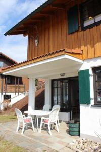 un patio con sillas blancas y una mesa frente a una casa en Ferienhaus Alpkönig in Missen mit Garten und Terrasse, en Missen-Wilhams