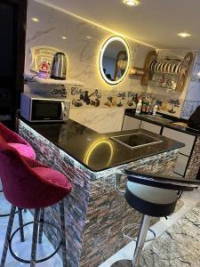 a kitchen with a counter with a sink and two bar stools at شاليهات اهرامات بورتو السخنة in Ain Sokhna