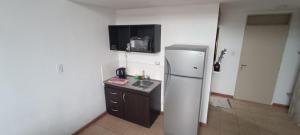 a small kitchen with a refrigerator and a sink at La Via Apart in Bahía Blanca