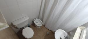 La salle de bains blanche est pourvue de toilettes et d'un bidet. dans l'établissement La Via Apart, à Bahía Blanca