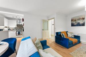 a living room with a blue couch and a kitchen at Secret Abode in Harrogate in Harrogate