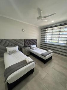 a bedroom with two beds and a ceiling fan at Feels Like Home Condo Victoria Falls in Victoria Falls