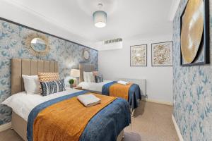 two beds in a room with blue and white wallpaper at Secret Abode in Harrogate in Harrogate