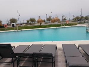 una piscina con 2 sillas y una mesa en Bajo con jardin en primera línea de playa, en Málaga