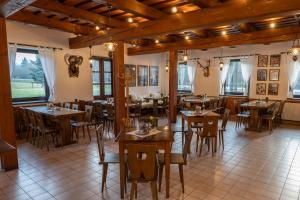 um restaurante com mesas e cadeiras de madeira e janelas em Koliba Pod Horů em Dolní Bečva