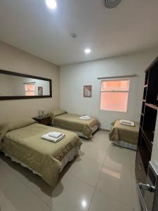 um quarto com três camas e uma janela em Gran Hotel Laserre em Rio Grande