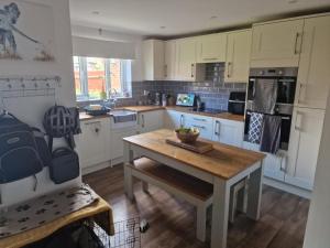 a kitchen with white cabinets and a wooden table at 7 Ash Close in Rolstone